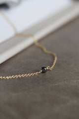 Alaia halskæde i 14 karat guld og enkel, sort diamant. Kæden er en rund ankerkæde. POMPUS smykker er håndlavet og fra eget værksted her i Danmark