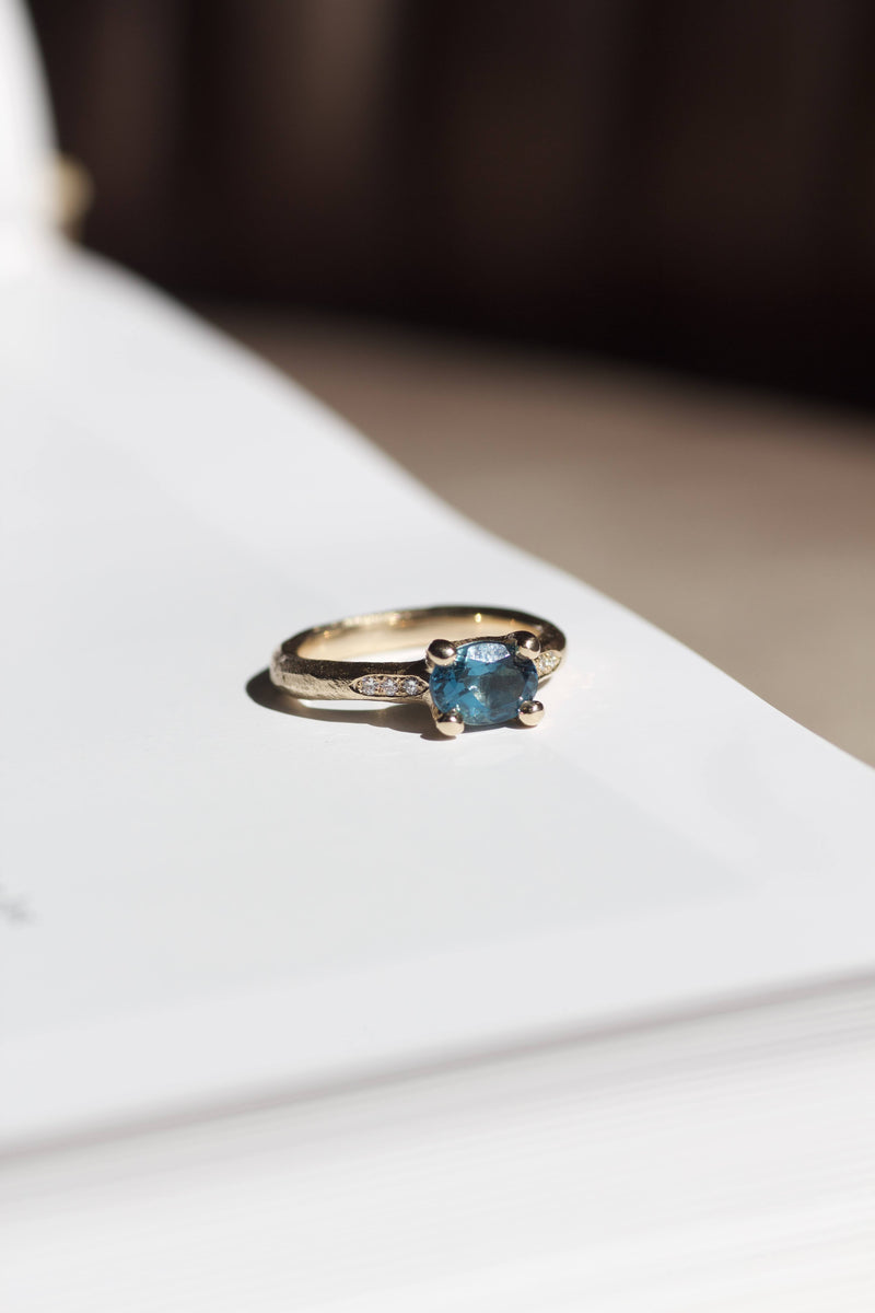 Rustik guldring i 14 karat guld med smuk london blå turmalin samt brillater på siderne. All about ringene skal male verden i farver og symboliserer alt, der giver værdi for den, der bærer den. Mens de emmer af farver og liv, gemmer de på et tomt lærred, der venter på sin historie og betydning. Hvad skal de symbolisere for dig? 